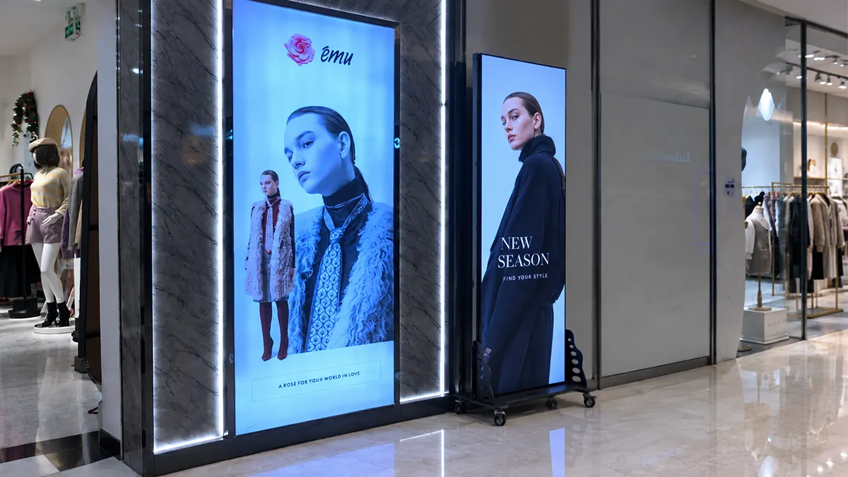 LED poster screen next to retail lightbox in a mall corridor
